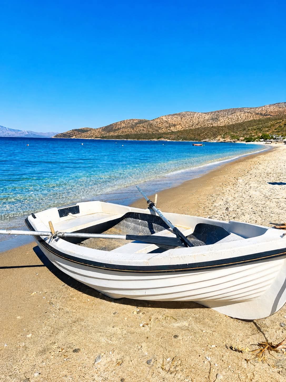 Παραδοσιακή βάρκα σε αμμώδη παραλία με γαλάζια νερά